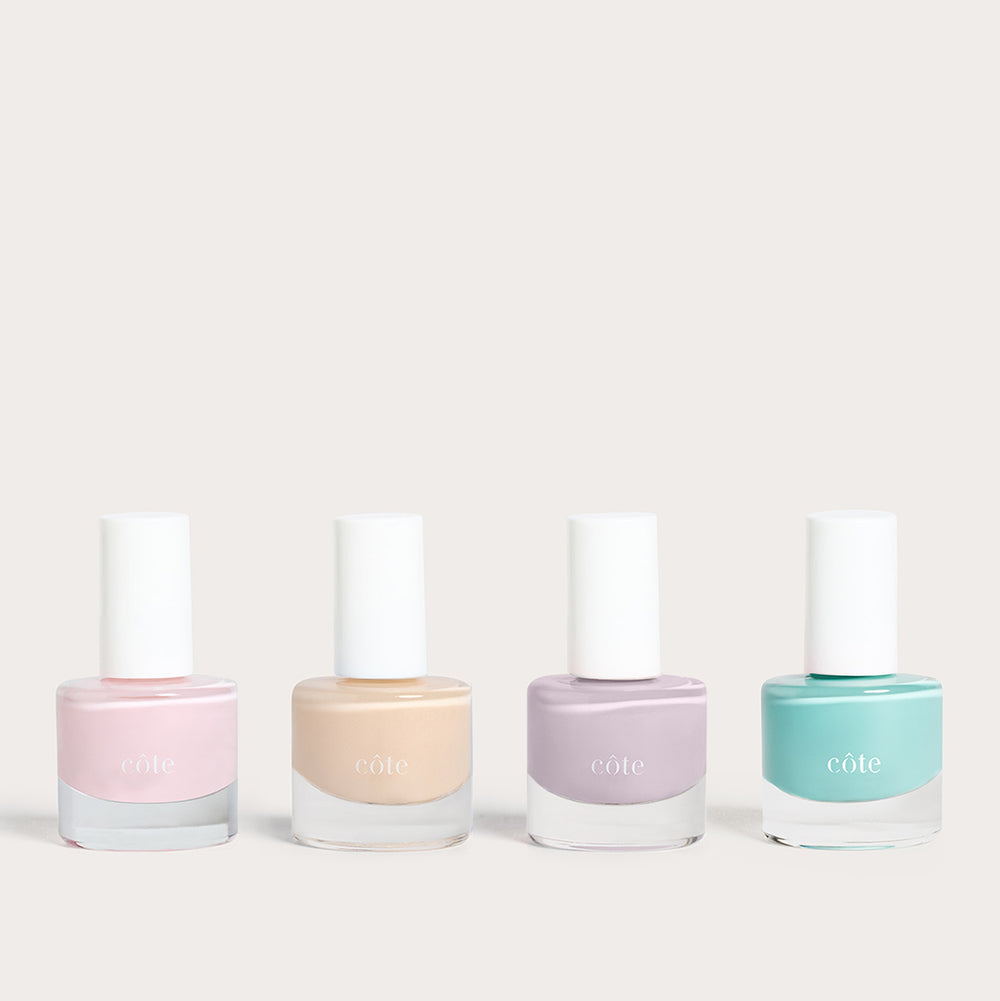 Côte Beauty Summer Vows Set, four nail polish bottles in blush pink, nude beige, soft violet grey and fresh aqua blue on a neutral background.